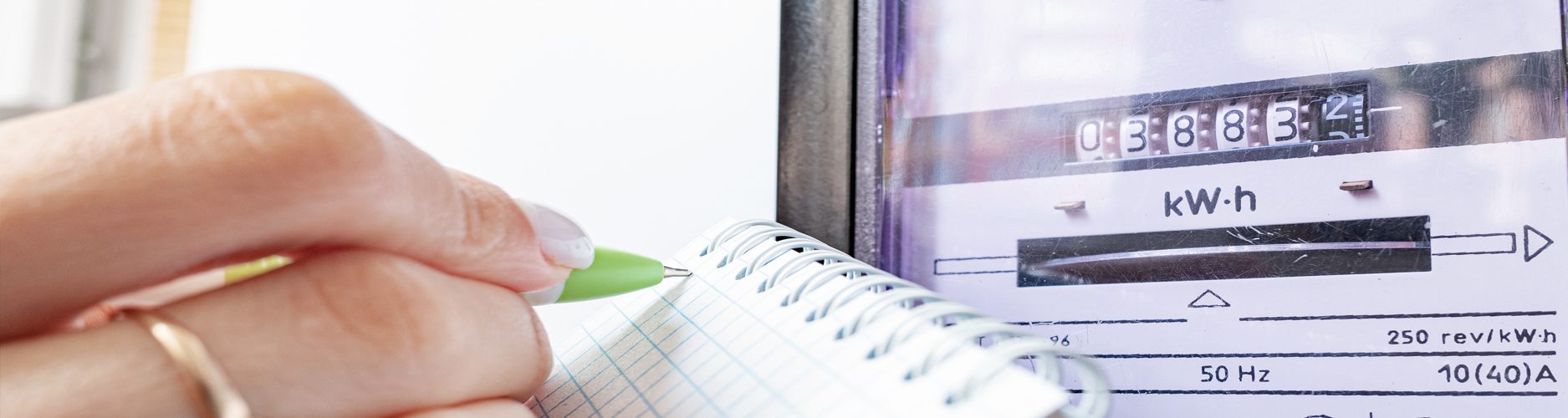 Foto: Frau hält Kugelschreiber und notiert sich Stromzählerstand auf Block