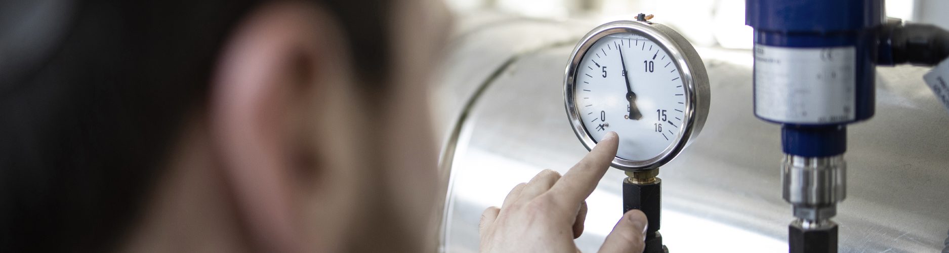 Foto: Mann schaut sich Manometer an und kontrolliert den Druck von Erdgas in Rohrleitungen